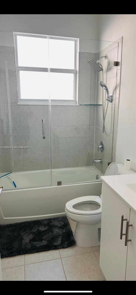 full bathroom with tile patterned flooring, a healthy amount of sunlight, bathing tub / shower combination, and toilet