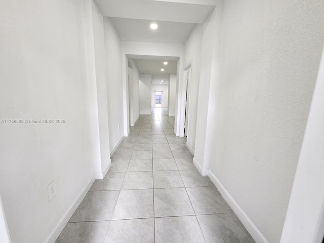 corridor with recessed lighting, light tile patterned flooring, and baseboards