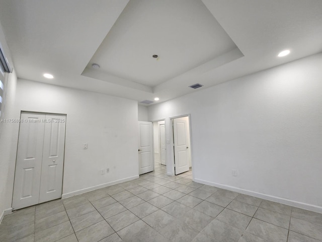 unfurnished room with recessed lighting, a raised ceiling, visible vents, and baseboards