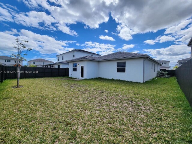 back of property with a lawn, a fenced backyard, and stucco siding