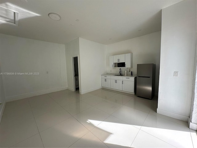 spare room featuring light tile patterned floors, baseboards, and a sink