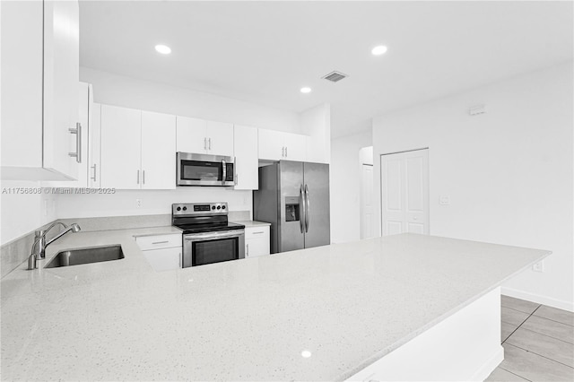 12735 SW 211th St, Miami, FL 33177 - kitchen with appliances with stainless steel finishes, a sink, light stone counters, white cabinetry, and a peninsula