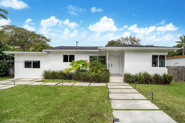 ranch-style home featuring a front yard, fence, and stucco siding