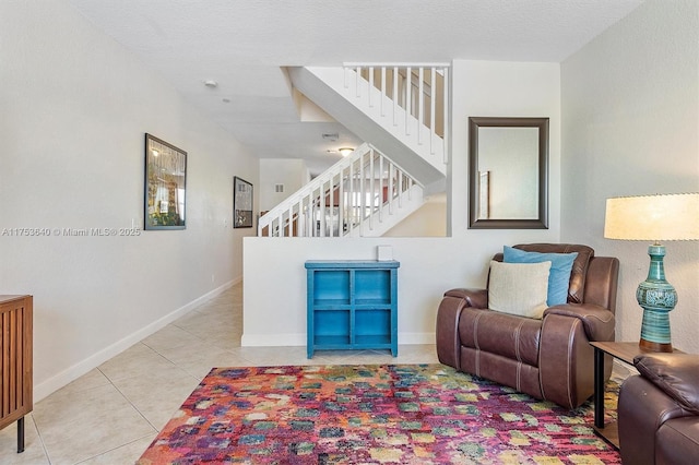 tiled living area featuring stairs and baseboards