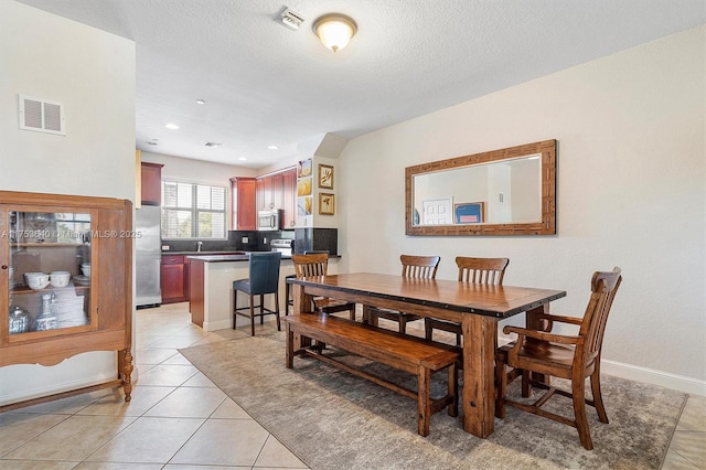 dining area featuring visible vents, a textured ceiling, baseboards, and light tile patterned floors