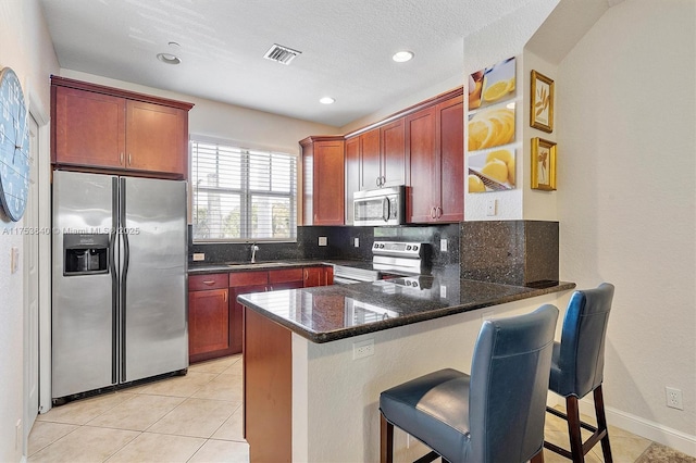 kitchen featuring tasteful backsplash, visible vents, a peninsula, stainless steel appliances, and a sink