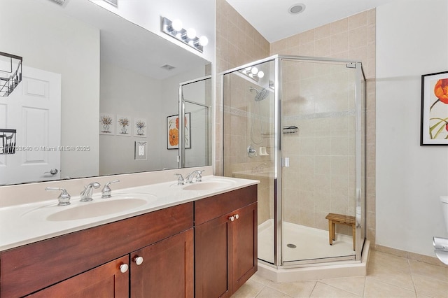 full bath with double vanity, a sink, a shower stall, and tile patterned floors