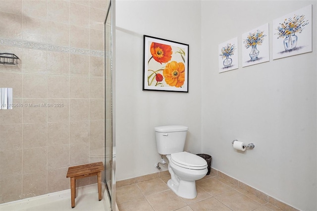 full bath with a stall shower, tile patterned flooring, baseboards, and toilet