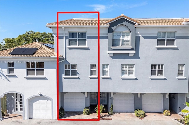 1835 N Dixie Hwy, Fort Lauderdale, FL 33305 - view of front facade featuring a tile roof, roof mounted solar panels, a garage, and stucco siding
