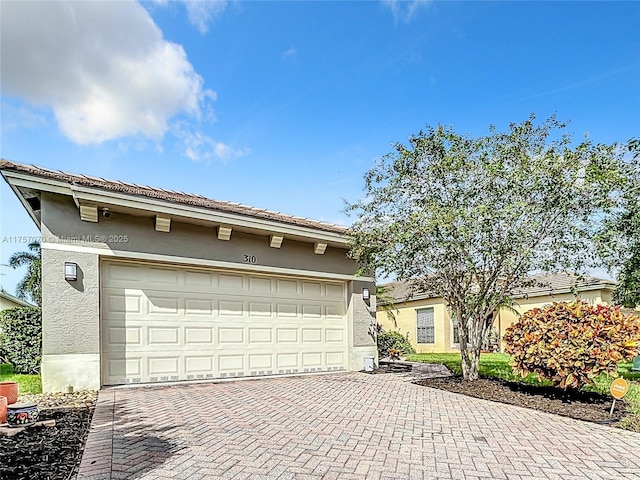 view of front facade with decorative driveway, an attached garage, and stucco siding