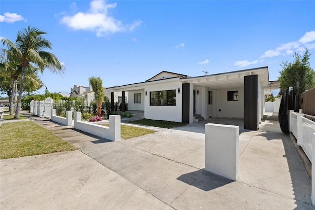 view of front of property with a carport, a fenced front yard, driveway, and stucco siding