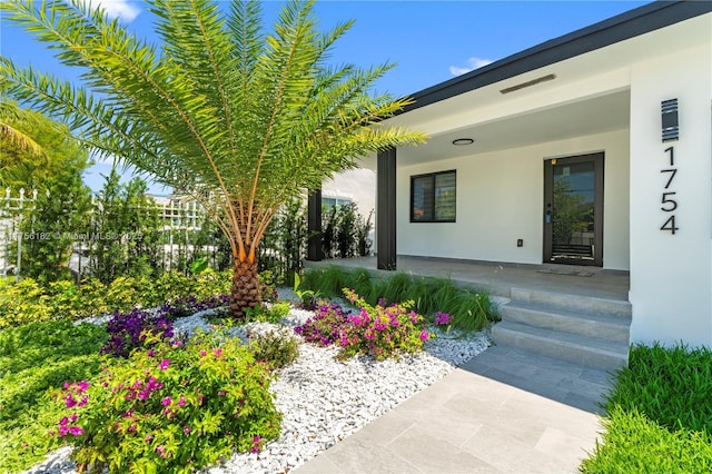 entrance to property featuring a porch and stucco siding
