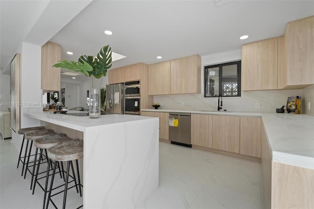 kitchen with stainless steel appliances, a sink, light brown cabinets, and modern cabinets