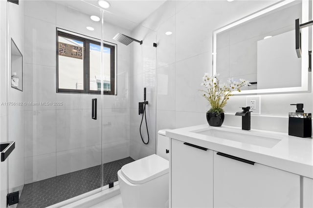full bath with tile walls, toilet, a stall shower, and vanity