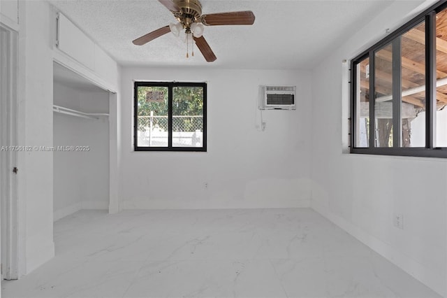 unfurnished bedroom featuring ceiling fan, a textured ceiling, a closet, marble finish floor, and an AC wall unit
