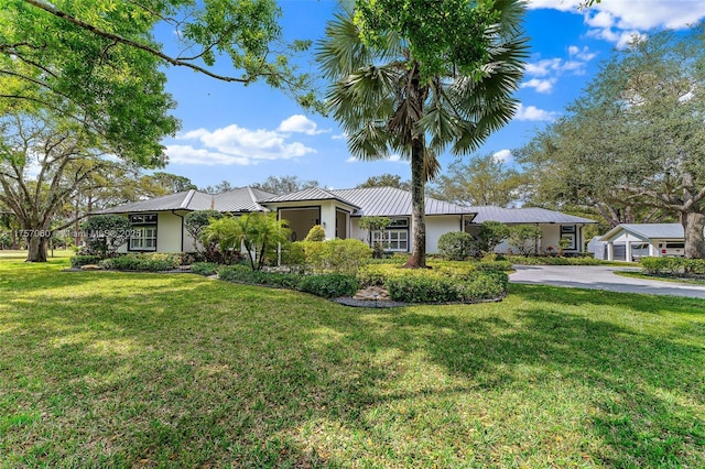 single story home with a standing seam roof, a front lawn, metal roof, and stucco siding