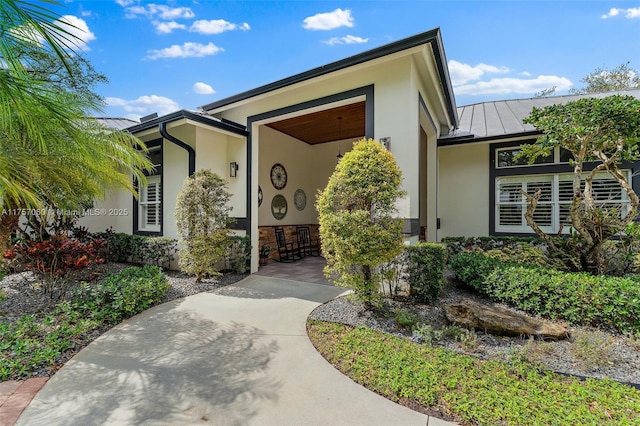 view of exterior entry featuring a standing seam roof, metal roof, and stucco siding