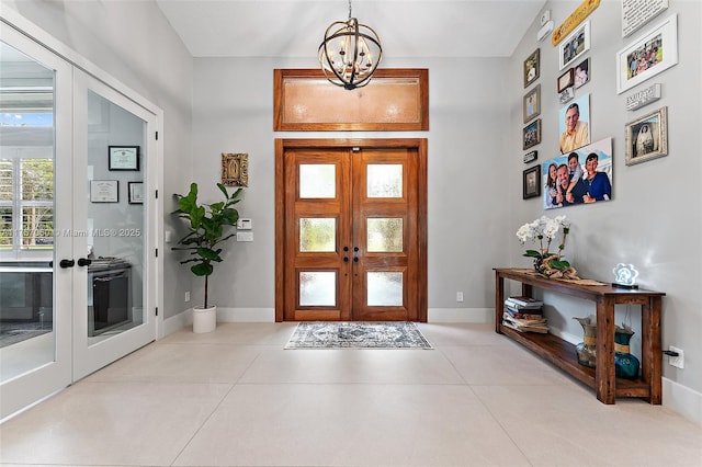 entryway with tile patterned flooring, french doors, baseboards, and an inviting chandelier