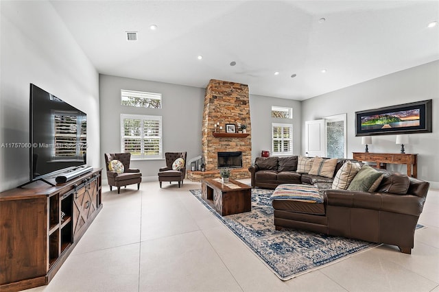 living area featuring light tile patterned floors, visible vents, a wealth of natural light, and a stone fireplace