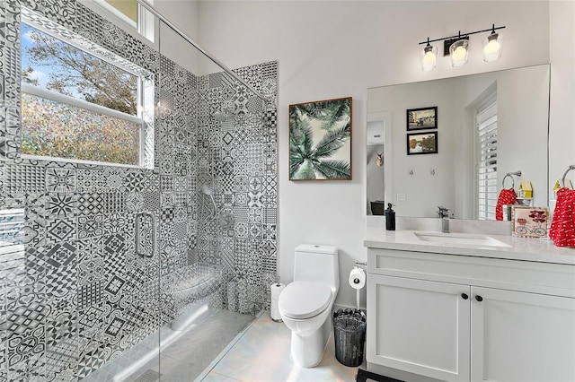 bathroom featuring a tile shower, vanity, and toilet