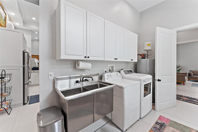 washroom with light tile patterned floors, recessed lighting, water heater, cabinet space, and washer and clothes dryer