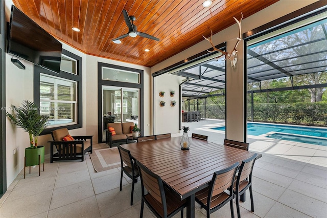 view of patio with a lanai, a pool with connected hot tub, a ceiling fan, and outdoor dining space