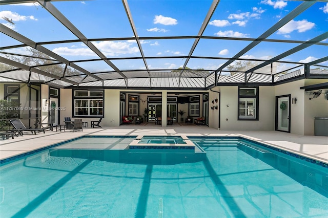 view of pool featuring a patio area, a pool with connected hot tub, and glass enclosure