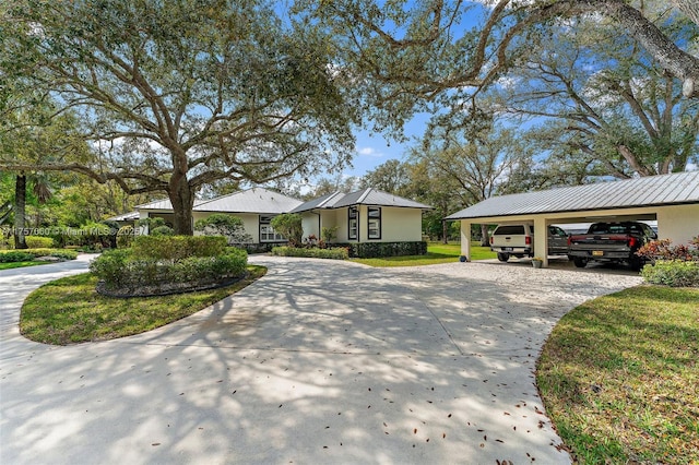 exterior space with a garage, concrete driveway, metal roof, a front yard, and stucco siding