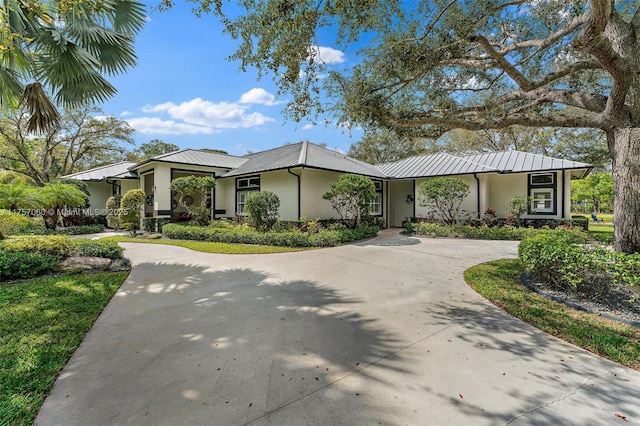 view of front of property featuring metal roof, driveway, and stucco siding