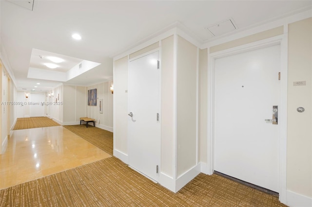 corridor featuring a raised ceiling, attic access, and recessed lighting