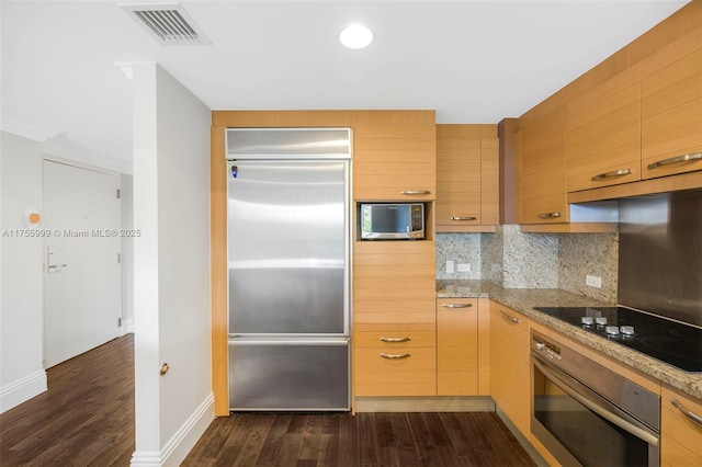 kitchen featuring stainless steel appliances, visible vents, light stone countertops, tasteful backsplash, and dark wood finished floors