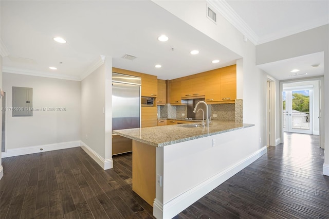 kitchen featuring electric panel, visible vents, built in appliances, a peninsula, and crown molding