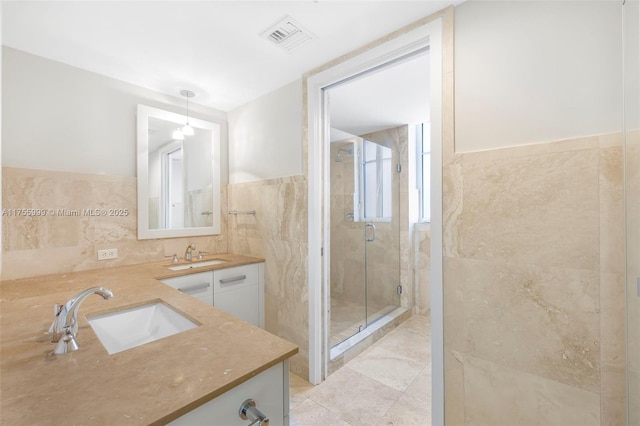 full bath with tile walls, visible vents, a sink, and a stall shower