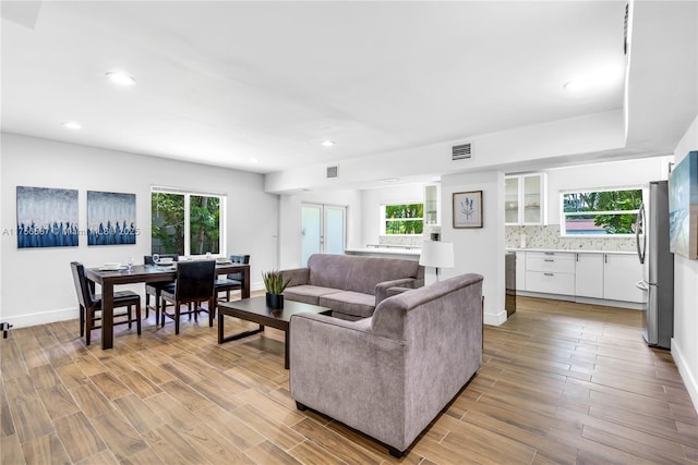 living room featuring wood finish floors, visible vents, baseboards, and recessed lighting