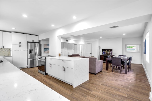 kitchen featuring visible vents, appliances with stainless steel finishes, white cabinets, and wood finished floors