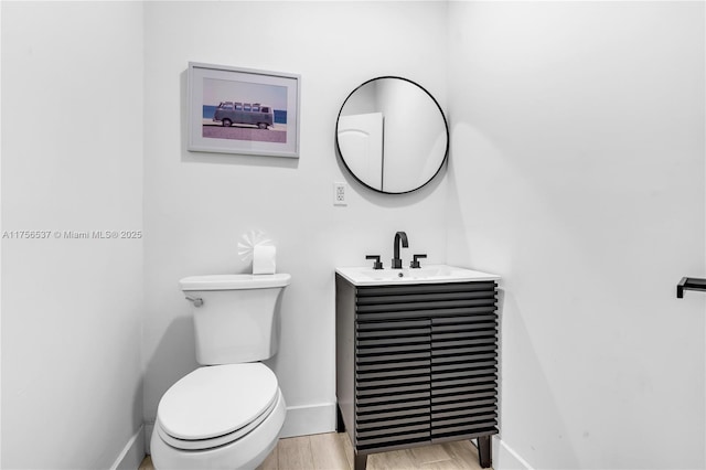 bathroom featuring baseboards, vanity, toilet, and wood finished floors