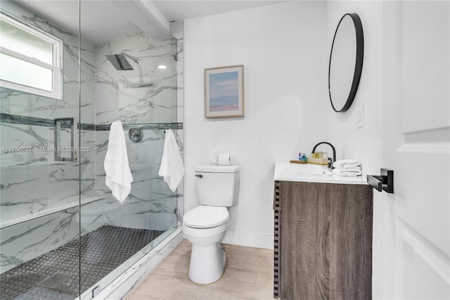 full bathroom with wood finish floors, a marble finish shower, toilet, vanity, and baseboards