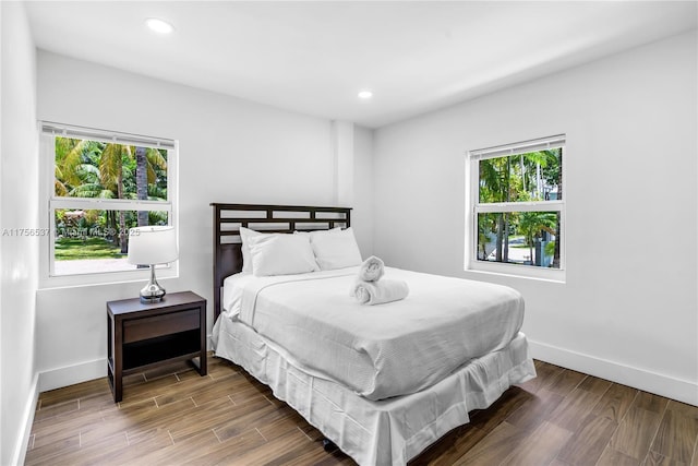 bedroom with baseboards, wood finished floors, and recessed lighting