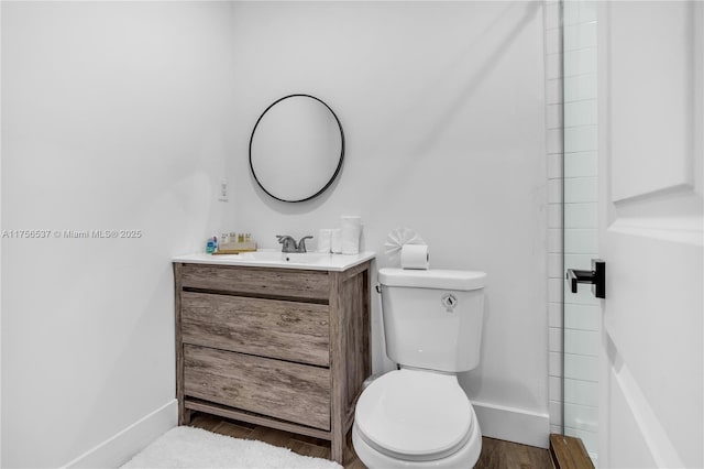 bathroom featuring toilet, baseboards, wood finished floors, and vanity