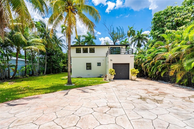 exterior space featuring concrete driveway, a balcony, stucco siding, an attached garage, and a front yard