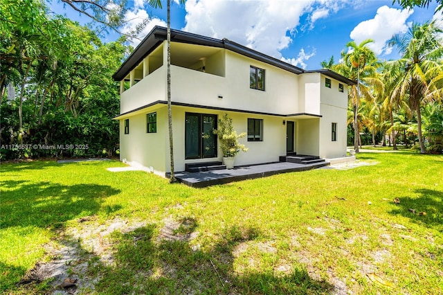 back of property featuring a lawn and stucco siding