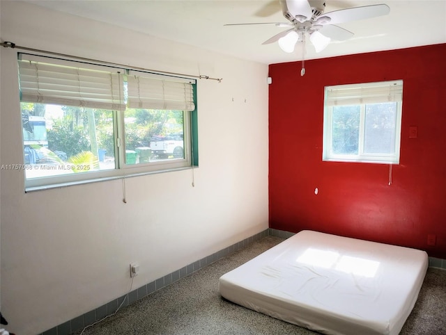 unfurnished bedroom featuring ceiling fan, baseboards, and speckled floor