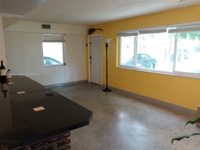 interior space with visible vents, baseboards, and speckled floor