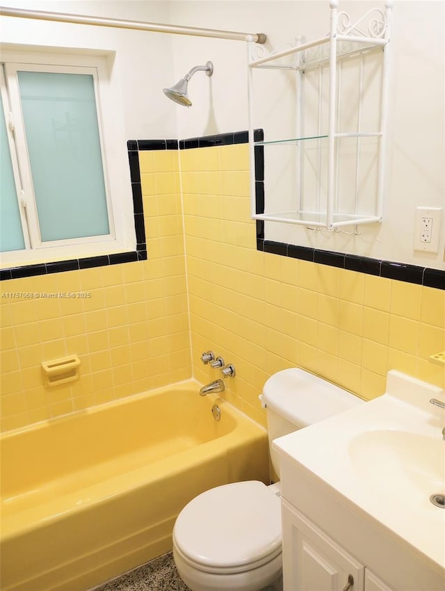 bathroom with vanity, tile walls, toilet, and bathing tub / shower combination