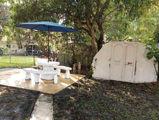 view of yard featuring a patio area, an outdoor structure, a storage shed, and fence