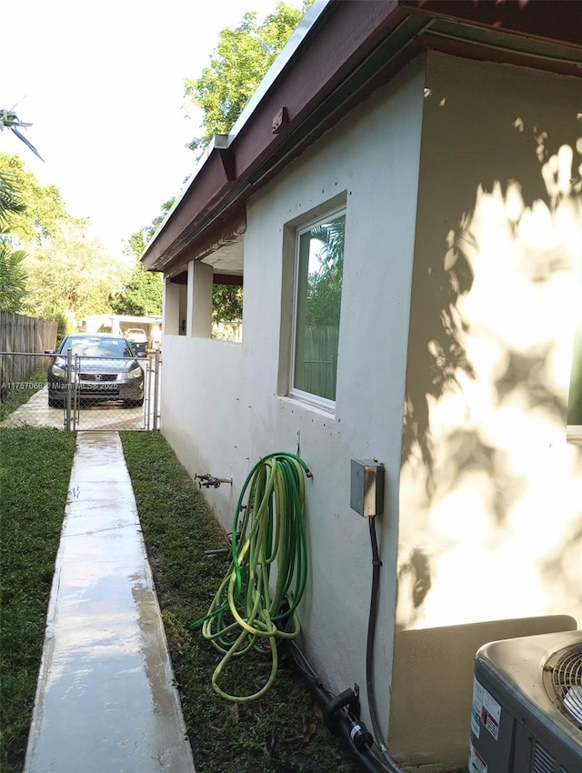 view of side of property featuring central air condition unit, fence, and stucco siding