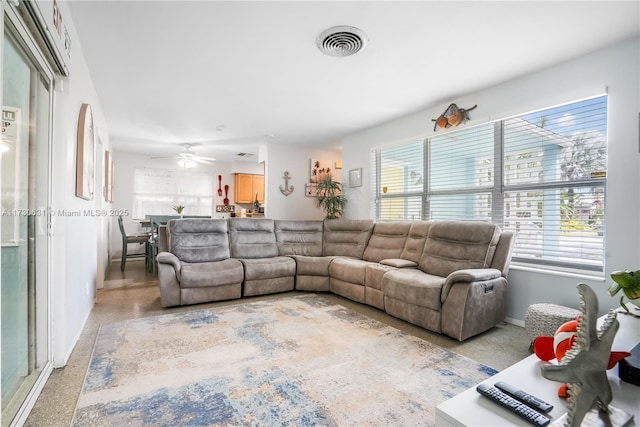 living room featuring plenty of natural light, visible vents, light speckled floor, and baseboards