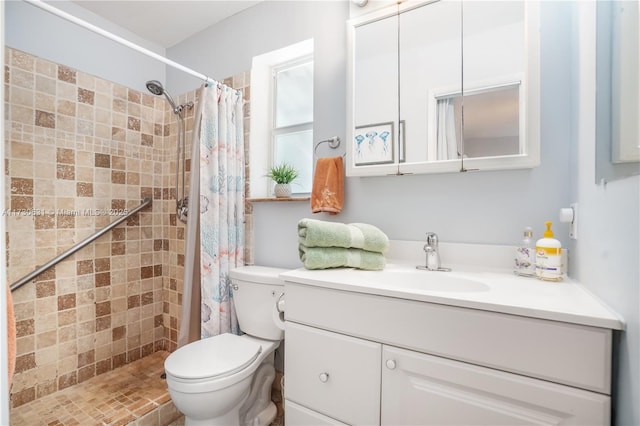 bathroom with toilet, tiled shower, and vanity