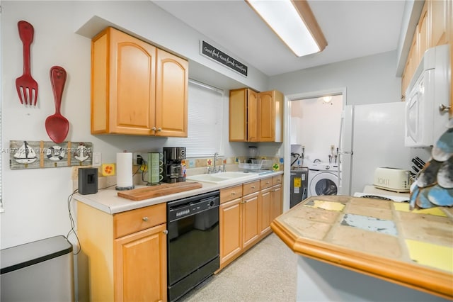 kitchen featuring black dishwasher, light countertops, light brown cabinetry, freestanding refrigerator, and a sink