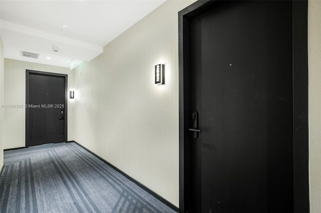 corridor with carpet floors, baseboards, and visible vents